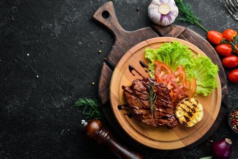 Premium Photo Juicy Baked Pork Steak With Vegetables On The Board Top View