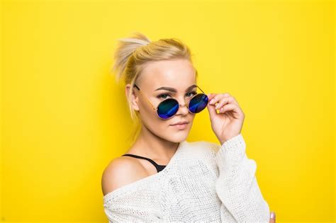 Fille Blonde De Mode En Pull Blanc Moderne En Lunettes De Soleil Bleu Brillant Pose Sur Jaune