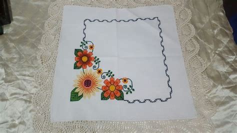 A White Doily With Flowers On It Sitting On Top Of A Lace Tablecloth