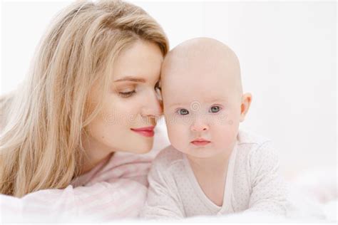 La Jeune Belle Mère Blonde Du Caucase Se Trouve Sur Le Lit Avec Sa Fille De Bébé La Maison