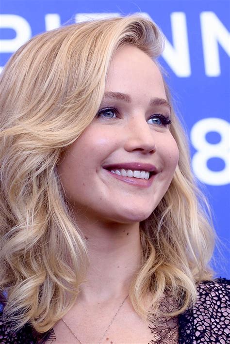 A Woman With Blonde Hair And Blue Eyes Smiles At The Camera While Wearing A Black Dress
