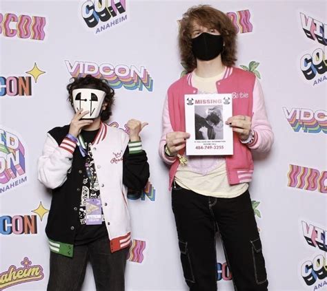 Two People Standing Next To Each Other With Masks On Their Faces And