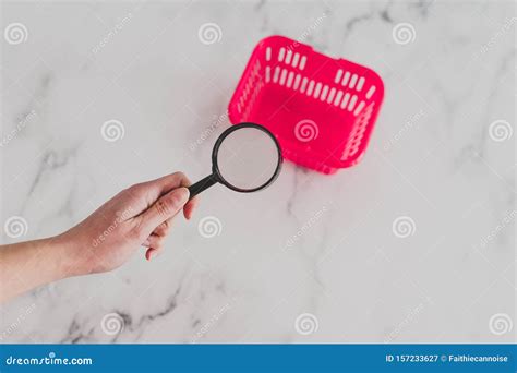 Hand Holding Magnifying Glass Over The Word Pink Basket On Marble Desk