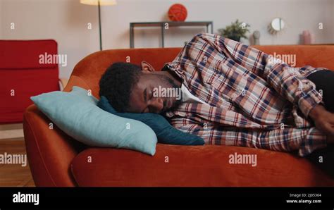 Exhausted Overworked African American Man Falling Asleep On Sofa After