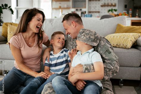 Happy soldier sitting on the floor with his family. Soldier and his wife enjoying at home with ...