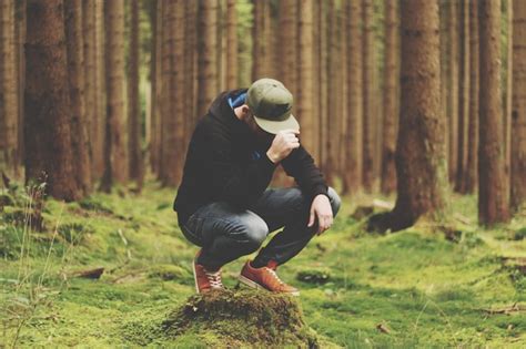 Premium Photo Full Length Of Man Wearing Cap While Crouching In Forest