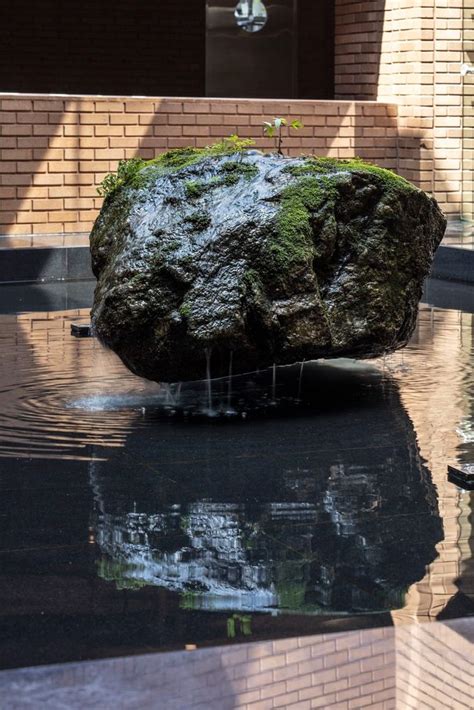 A Large Rock Sitting In The Middle Of A Pool Of Water Next To A Brick