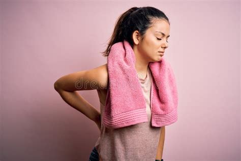 Joven Y Hermosa Deportista De Brunette Con Ropa Deportiva Y Toalla Sobre Fondo Rosa Con Dolor De