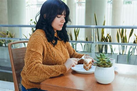 Vista De Perfil Retrato De Una Joven Latina Muy Feliz Sentada Comiendo Pastel De Zanahoria En Su