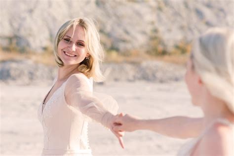 Dos mujeres novias en vestido blanco con cabello rubio abrazándose