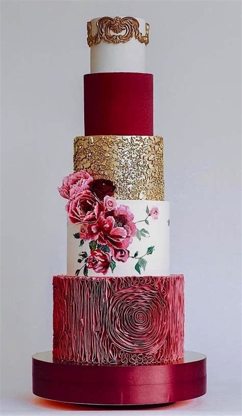 A Multi Tiered Cake With Gold And Red Decorations On Its Sides