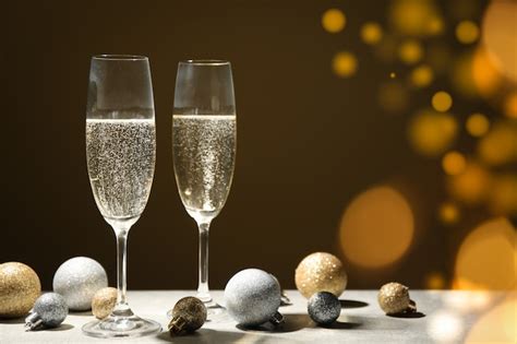 Premium Photo Baubles And Champagne Glasses On Decorated Space Bokeh