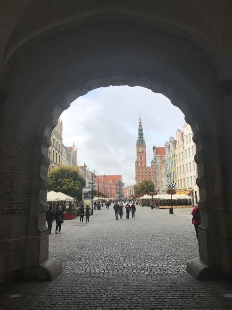 People Walking Through An Archway In The Middle Of A City