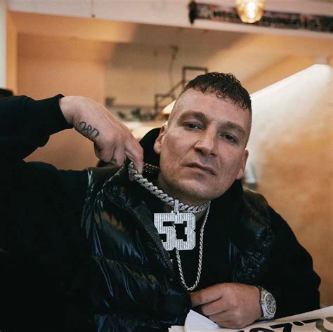 a man in a black jacket is sitting down with his hands on his hips and ...
