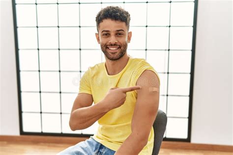 Arab Young Man Getting Vaccine Showing Arm With Band Aid Smiling Happy