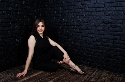 Premium Photo Portrait Of A Beautiful Brunette Girl In Black Jumpsuit Sitting And Posing
