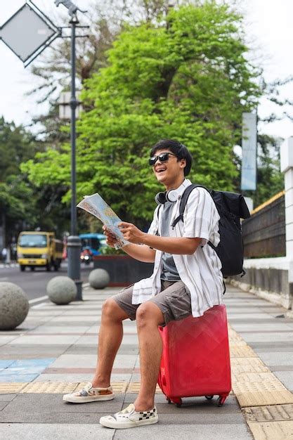 Homem Turista Sentado Na Mala E Segurando O Mapa Da Cidade Parecendo