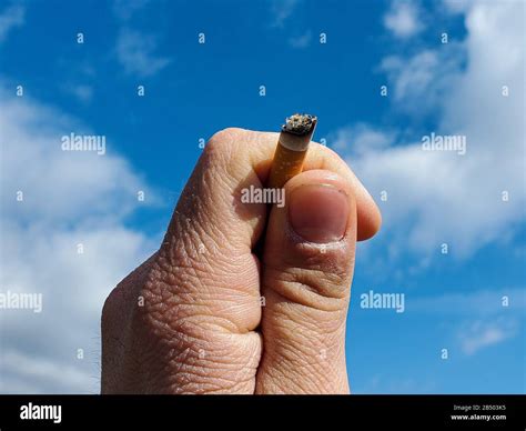 Human Hand Hold Tobacco Cigarette Over On Blue Sky Background Smoking