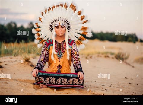 American Indian woman sitting in yoga pose. Headdress made of feathers ...