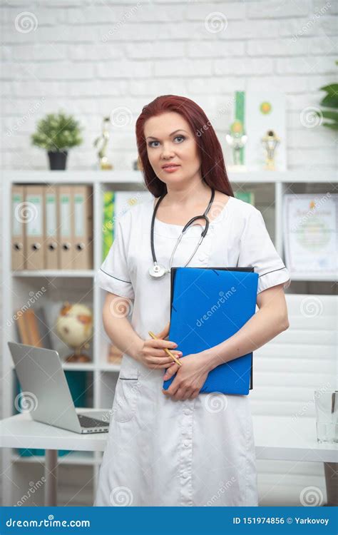 Smiling Female Doctor In Uniform With A Stethoscope And A Blue Folder