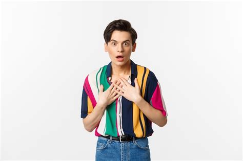 Retrato de hombre gay sorprendido cogidos de la mano en el corazón mirando con incredulidad y