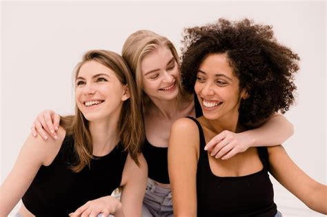 Jolie jeune fille blonde caucasienne étreignant ses copines interraciales en hauts noirs sur