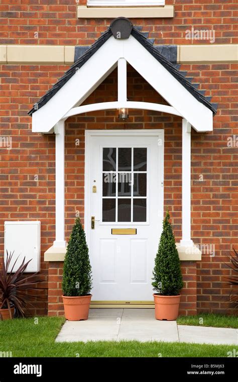 new red brick house with white front door and trees Stock Photo - Alamy