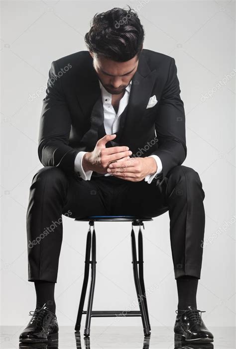 Man In Tuxedo Looking Down While Sitting On A Stool Stock Photo