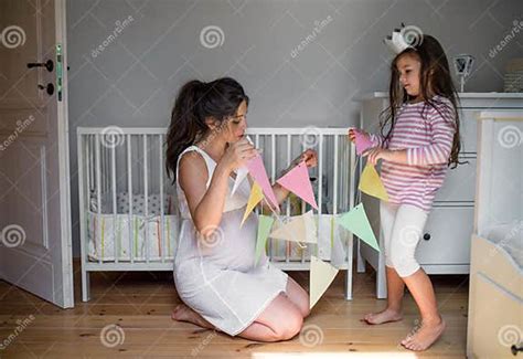 Portrait Of Pregnant Woman With Small Daughter Indoors At Home