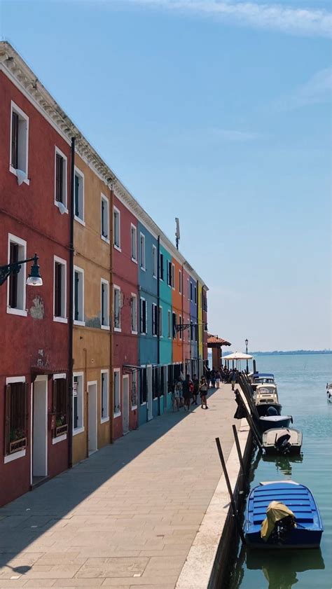 Several Boats Are Docked In The Water Next To A Row Of Multi Colored