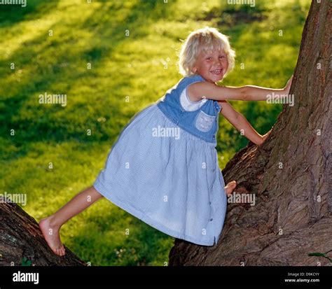 A Smiling Pretty Blonde Three Year Old Girl Having Fun Climbing Bare Footed In A Large