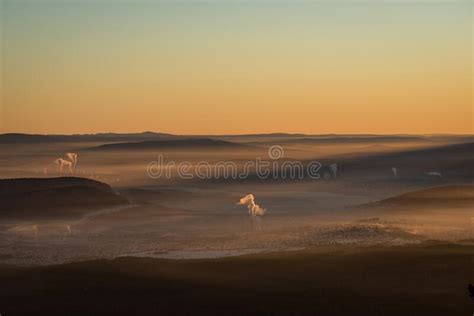 The Sun Sets Below The Horizon And Illuminates The Fog Hovering Over