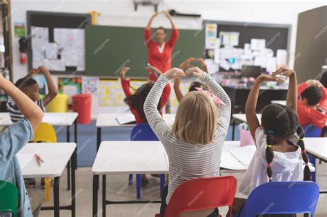Crianças Em Sala De Aula - Crianças da escola com os braços para cima brincando na sala de aula da ...