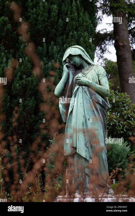 Una Escultura De Bronce De Una Anciana En Un Entorno De Parque De Pie