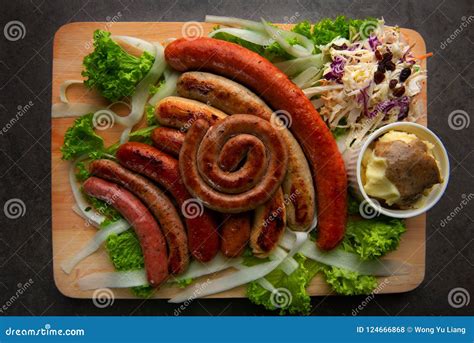 Зажаренные сосиски с картошками месива на деревянной доске Стоковое ...
