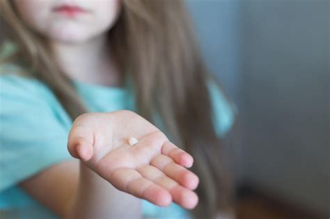 Portrait D Une Petite Fille Blonde Mignonne Enfant Tenant Et Montrant Sa Dent Avant De Lait