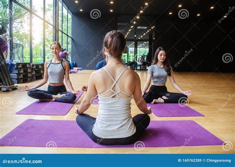 Young Sporty Women And A Group Of Sporty People Practicing Yoga Lesson