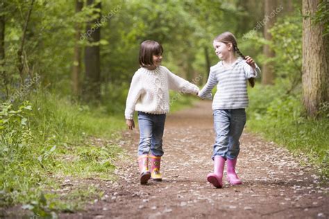 Two Sisters Walking On Path Holding Hands Smiling Stock Photo By