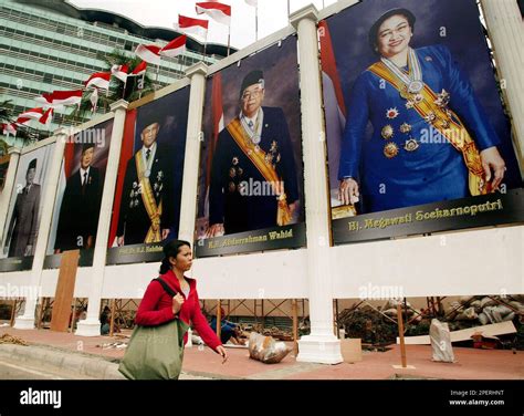 A Woman Walks Past By Large Posters Of Indonesian President Megawati