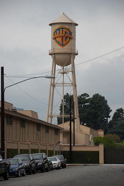 A Large Water Tower Sitting On The Side Of A Road Next To Cars Parked