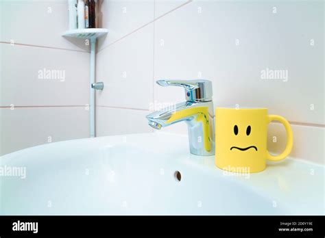 Chromed Metal Faucet For Hot And Cold Water Cup With Sad Face For Toothbrushes In A Modern