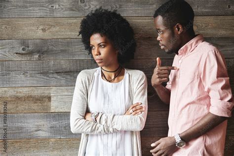 Dark Skinned Man Standing Next To His Offended Wife With Afro Haircut