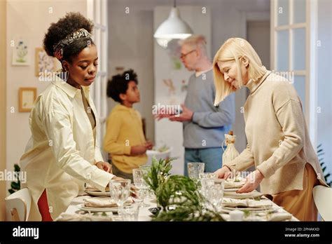 Une femme blonde mûre et sa belle fille afro américaine servant une table pour un dîner en