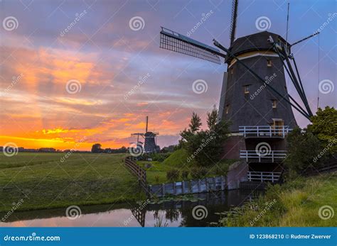 Three Wooden Windmills In A Row At Orange Sunset Stock Photo Image Of