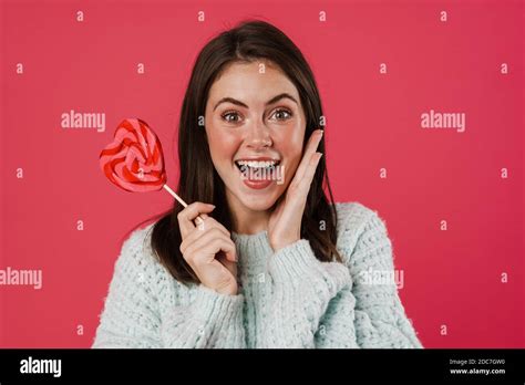 Image Of Excited Brunette Girl Smiling While Posing With Lollipop Isolated Over Pink Background