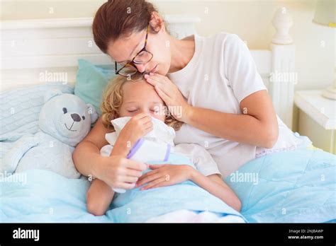 Niño enfermo en la cama Madre comprobando a un niño enfermo Niño