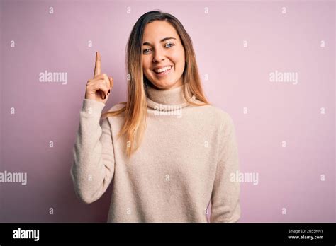 Belle femme blonde aux yeux bleus portant un pull à col roulé sur fond