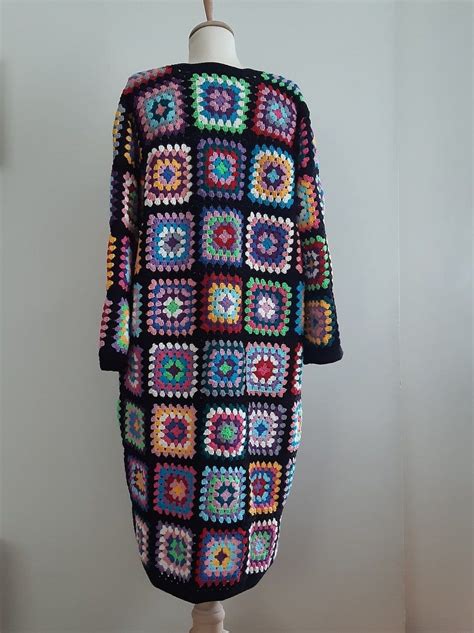 A Multicolored Crocheted Sweater Hanging On A Mannequin Head Stand