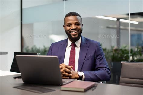 cheerful black businessman posing  workdesk  office stock photo