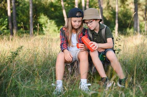 Girl And Boy Scout Sitting And Drinking Hot Tea From Thermos In The Woods Stock Photo Image Of